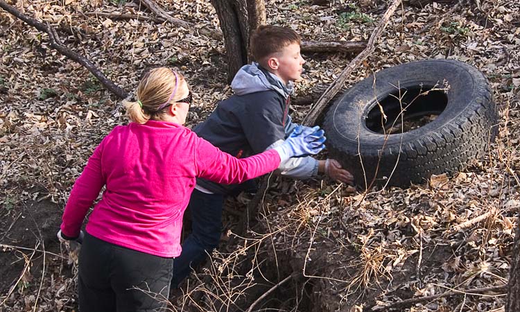Roots and Shoots volunteers wrestle a tire out of the gulley